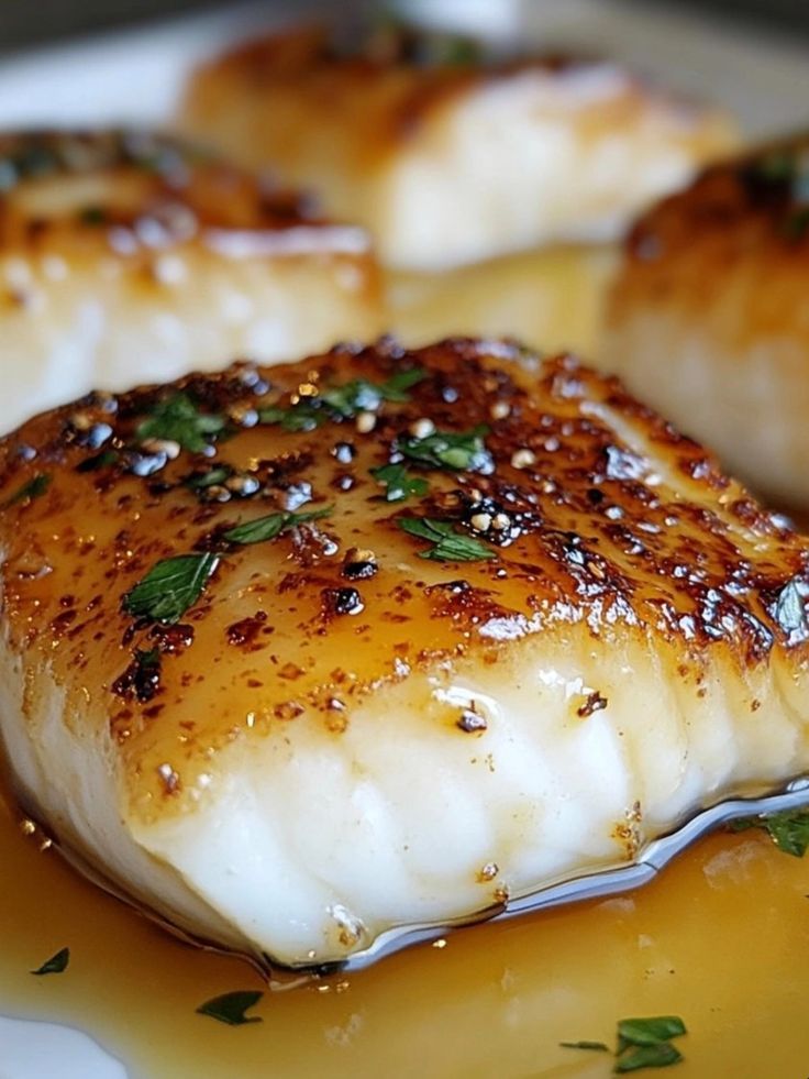 seared fish on a plate with sauce and herbs