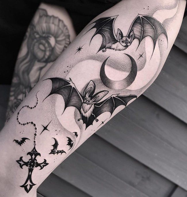 a woman's leg with tattoos on her legs and a bat flying through the air