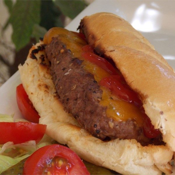 a close up of a hot dog with ketchup and tomatoes on the side