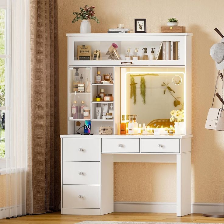 a white desk topped with a mirror and lots of drawers next to a window in a room