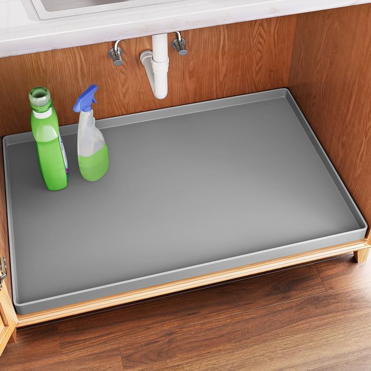 there is a tray with two bottles on it next to a sink and soap dispenser