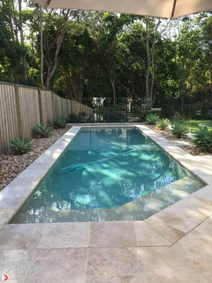 an empty swimming pool in the middle of a backyard with a large umbrella over it