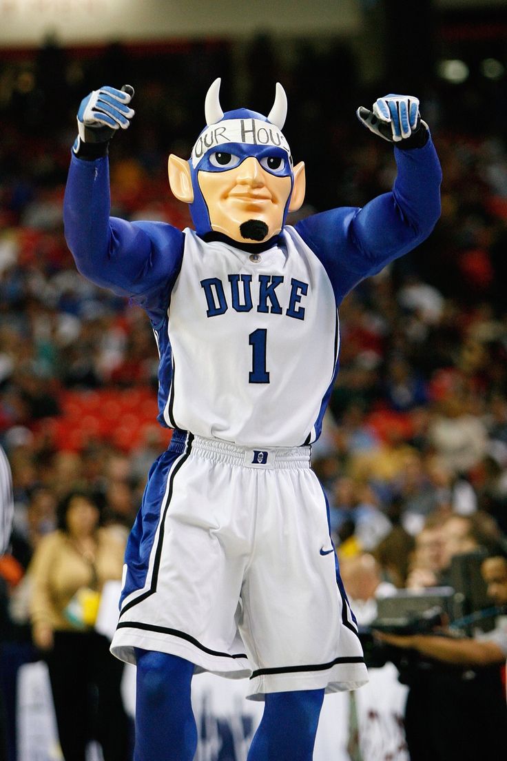 a man in a blue and white basketball uniform holding his hands up to the air