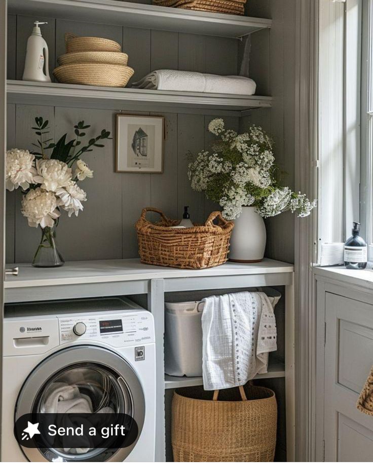 a washer and dryer sitting in a room next to some shelves with flowers