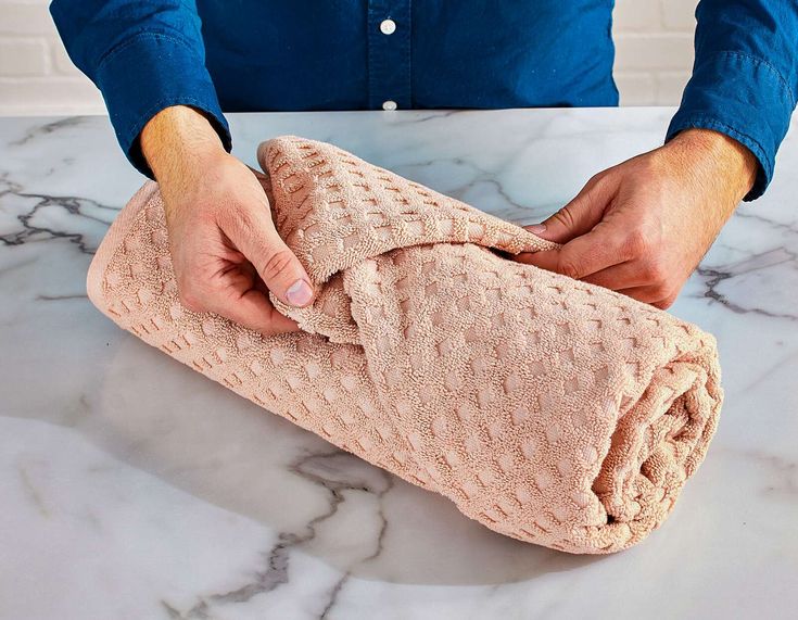 a person holding a pink blanket on top of a marble counter