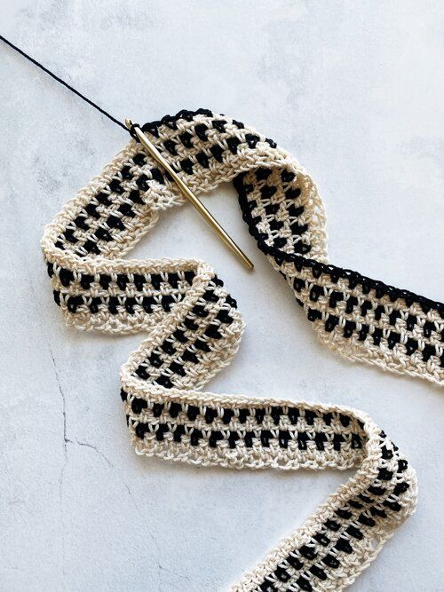 crocheted black and white scarf being worked on by a knitting machine with scissors