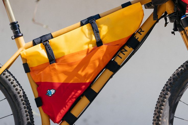 an orange and yellow flag is attached to the back of a bike's frame