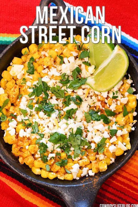 a skillet filled with corn, cheese and cilantro on top of a table