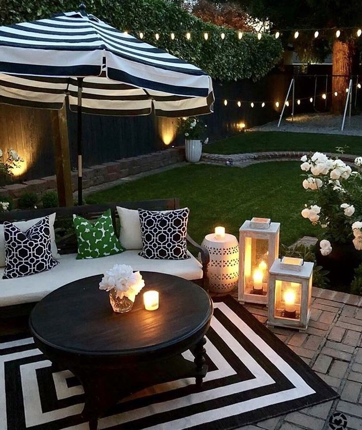 an outdoor living area with candles lit on the table and couches in the background