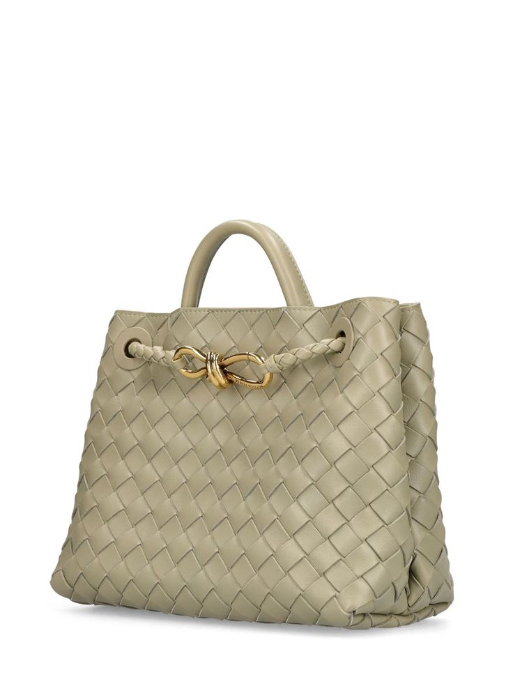 Find BOTTEGA VENETA Andiamo Leather Top Handle Bag on Editorialist. The BOTTEGA VENETA Andiamo bag features a woven leather construction, a knotted gold-tone clasp, a top handle, and a detachable shoulder strap. The bag also has a magnetic closure, two internal pockets, and one internal zip pocket. It measures 22cm in height, 25cm in width, and 10.5cm in depth. The strap drop is 50cm, and the top handle drop is 8cm. Luxury Bags With Braided Handles, Designer Bags With Braided Handles And Top Handle, Designer Bags With Top Handle And Braided Handles, Luxury Bags With Braided Round Handles, Designer Handheld Bags With Braided Handles, Elegant Bag With Woven Leather And Round Handle, Elegant Bags With Woven Leather And Round Handle, Elegant Shoulder Bag With Woven Leather And Round Handle, Designer Bags With Intrecciato Weave For Daily Use