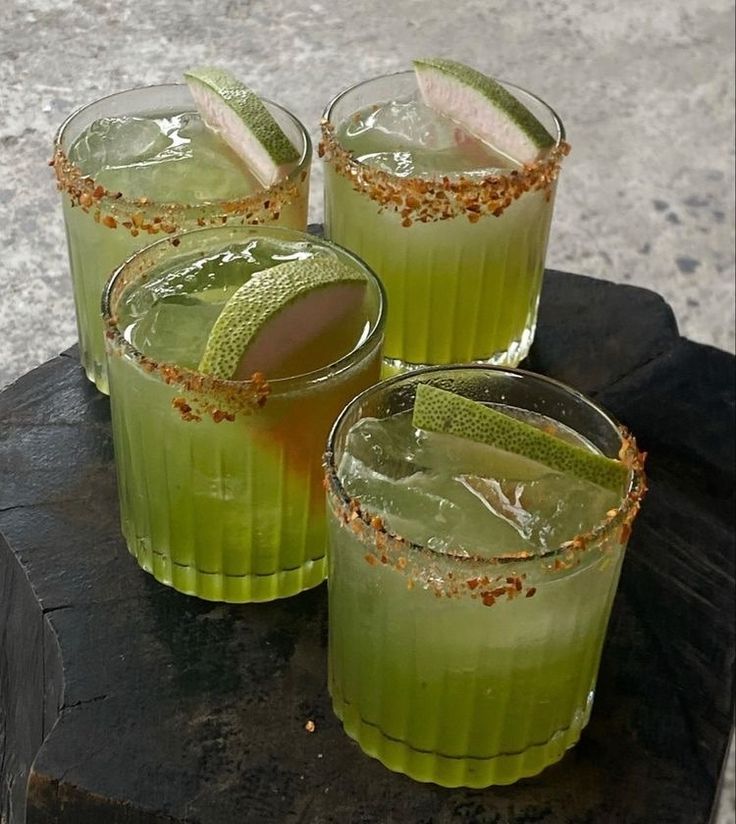 three glasses filled with green drinks sitting on top of a wooden table