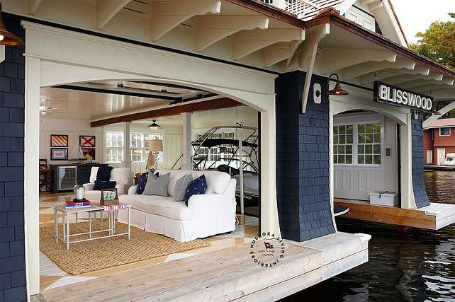 a living room with couches and chairs on the water's edge in front of a house