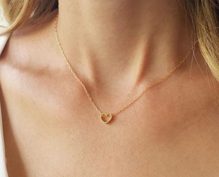 Bring some heart to your next look with our dainty gold necklace, with a stunningly 14K gold filled heart charm.   This delicate and dainty necklace is perfect for daytime wear. With its simple, open design, this 14k goldfilled necklace is sure to compliment any existing look.  This necklace is as versatile as it is beautiful and makes a stunning addition to any jewelry collection.  Add this piece to your own jewelry box or give this stunning necklace as a thoughtful gift to someone special. Necklace on model measures 16 inches choose your length from the drop down menu (15" - 18") Heart pendant measures 8mm. Photo 5 & 6- Sterling Silver necklace (choose your choice from the drop down menu)  ♥ Comes in a beautiful package ready for gifting.  View more dainty Necklaces: http://www.etsy.com/ First Mothers Day Gifts, Heart Outline, Packing Jewelry, Dainty Gold Necklace, Necklace Heart, Mom Necklace, Open Design, Wife Gift, Stunning Necklace