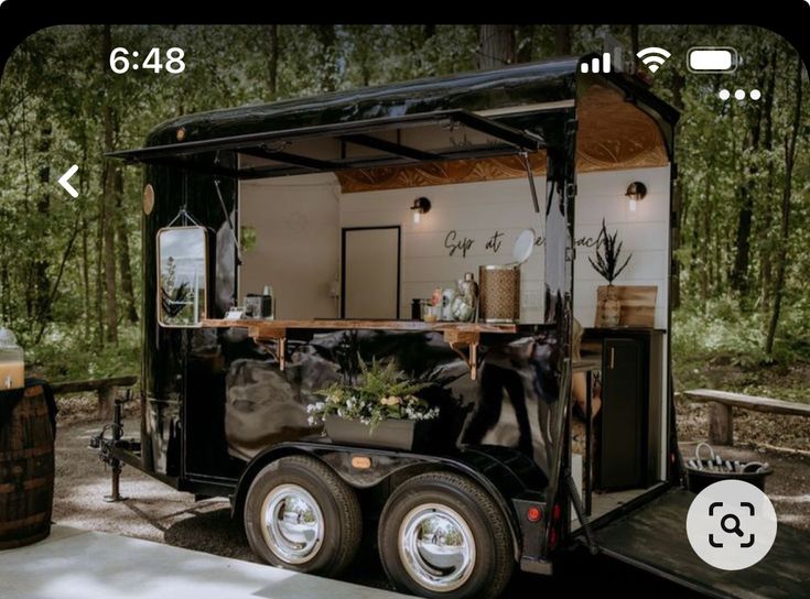 an image of a food truck with plants on the front and side walls, parked in a wooded area