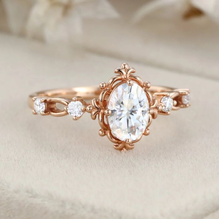 a close up view of a diamond ring on top of a white cloth with flowers in the background