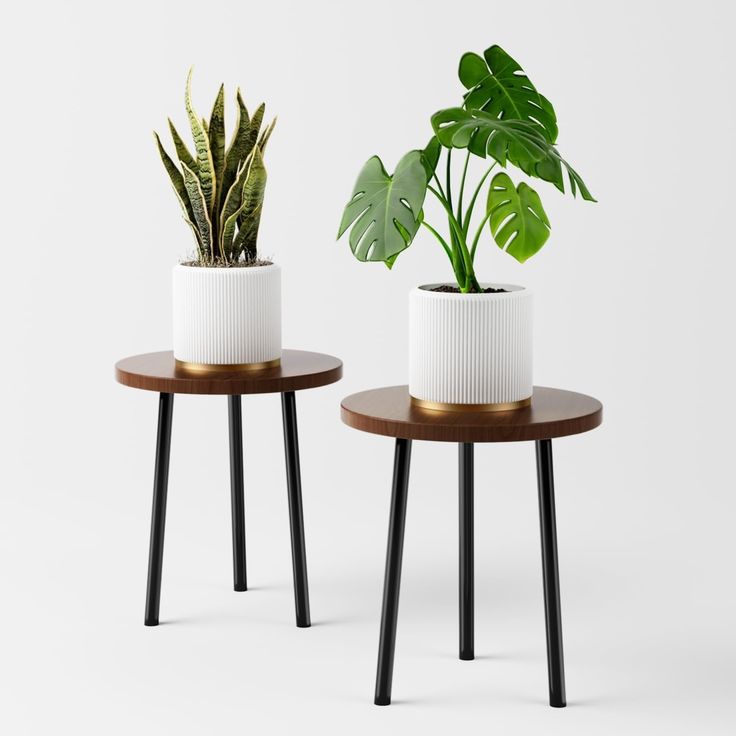 two white planters with black legs are sitting next to each other on small tables