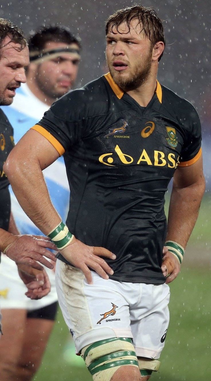 a rugby player is standing in the rain with his hands on his hips as he looks down