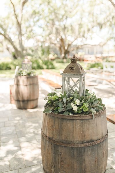 a wooden barrel with flowers and a lantern on top sits in the middle of a walkway