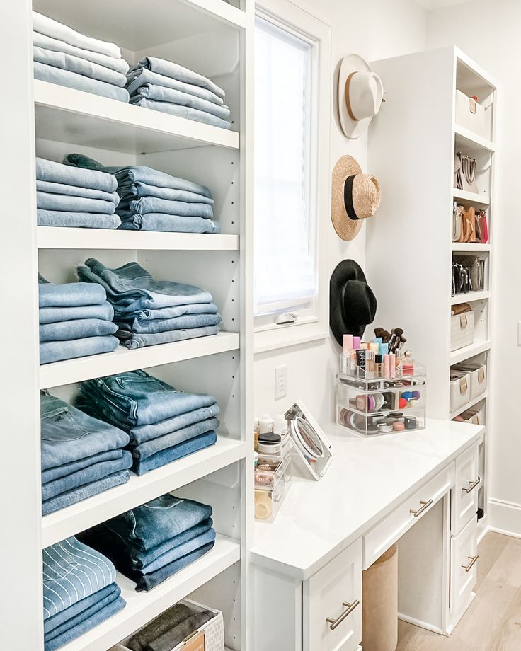 a white closet filled with lots of folded blue towels and other items on top of shelves