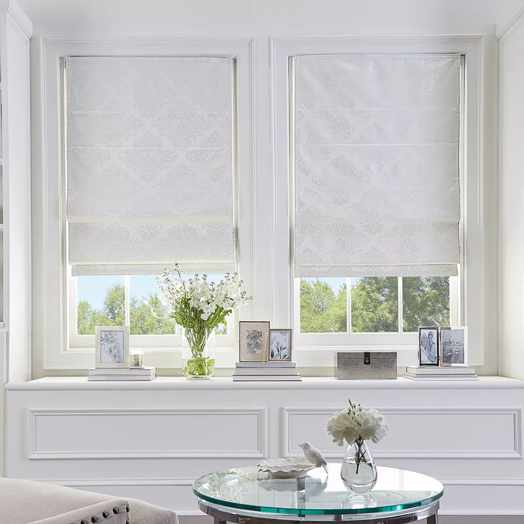 a living room filled with furniture and windows covered in white roman blind shades over the windows