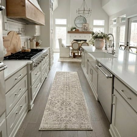 a kitchen with white cabinets and an area rug