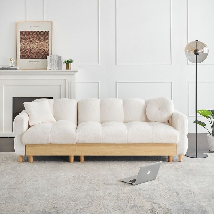 a living room with a white couch and laptop on the floor