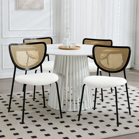 four chairs around a white table in a room with black and white rugs on the floor