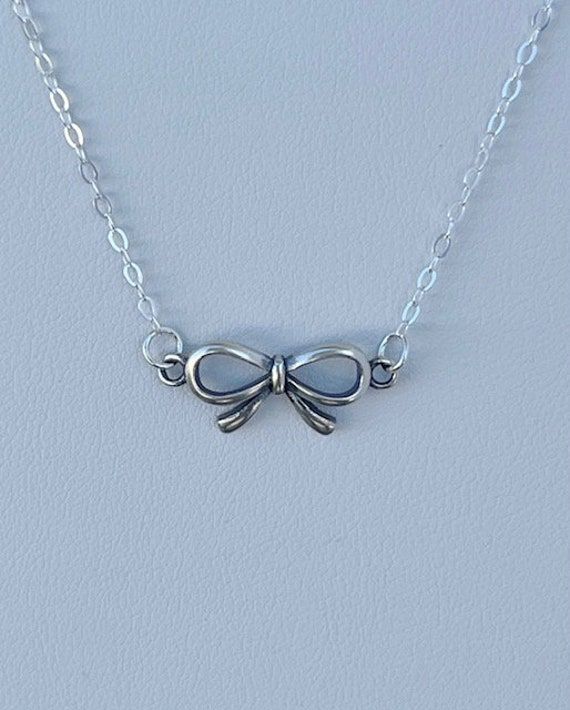 Small, sweet sterling bow hangs from a fine sterling chain with an alligator clasp closure. Cute Silver Charm Necklaces With Lobster Clasp, Cute Silver Charm Necklaces For Party, Cute Silver Jewelry With Adjustable Chain, Dainty Silver Charm Necklaces For Parties, Sterling Silver Charm Necklace With Delicate Chain For Party, Cute Sterling Silver Charm Necklace, Cute Jewelry With Butterfly Knot For Gifts, Dainty Sterling Silver Charm Necklaces For Parties, Cute Butterfly Knot Jewelry For Gifts