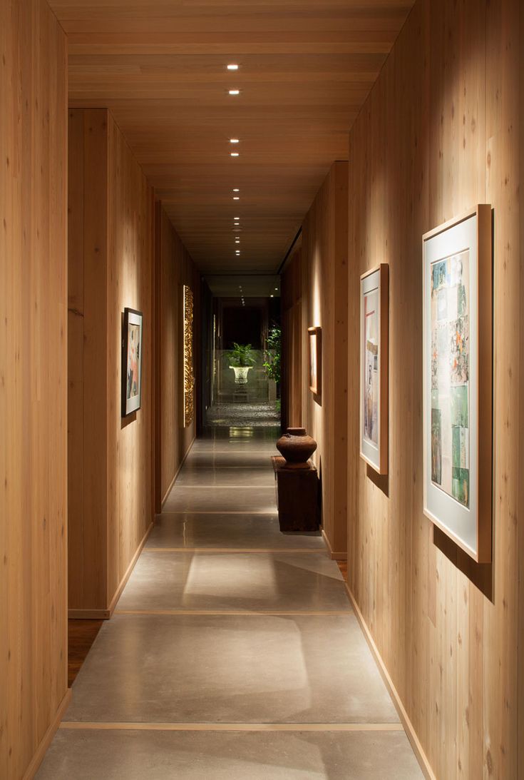 an empty hallway with wooden walls and pictures on the wall