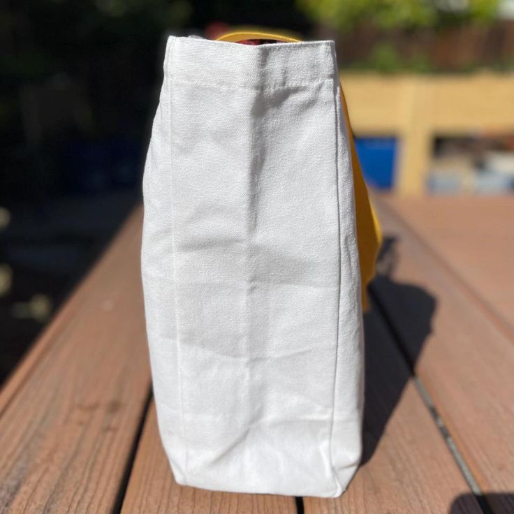 a white bag sitting on top of a wooden table next to a yellow banana peel