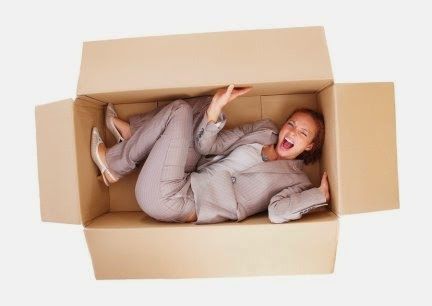 a woman laying in a cardboard box with her feet on the floor and mouth open