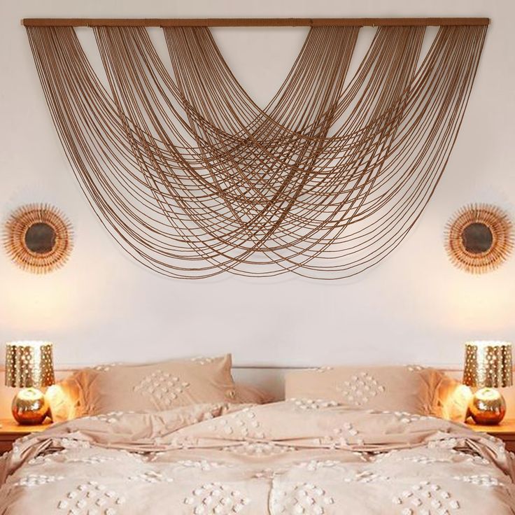 a bed with two lamps on either side of it and a string art hanging over the headboard