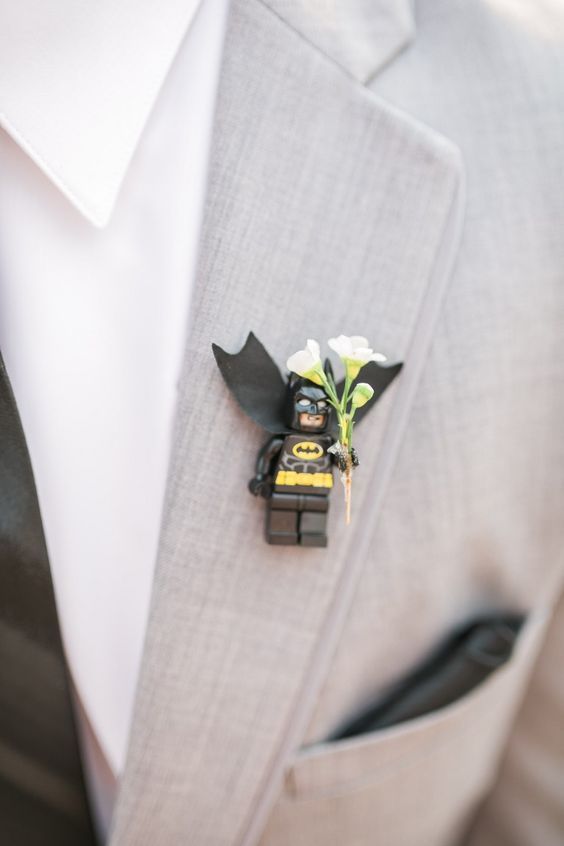 a lego batman boutonniere on a man's gray suit jacket and white shirt