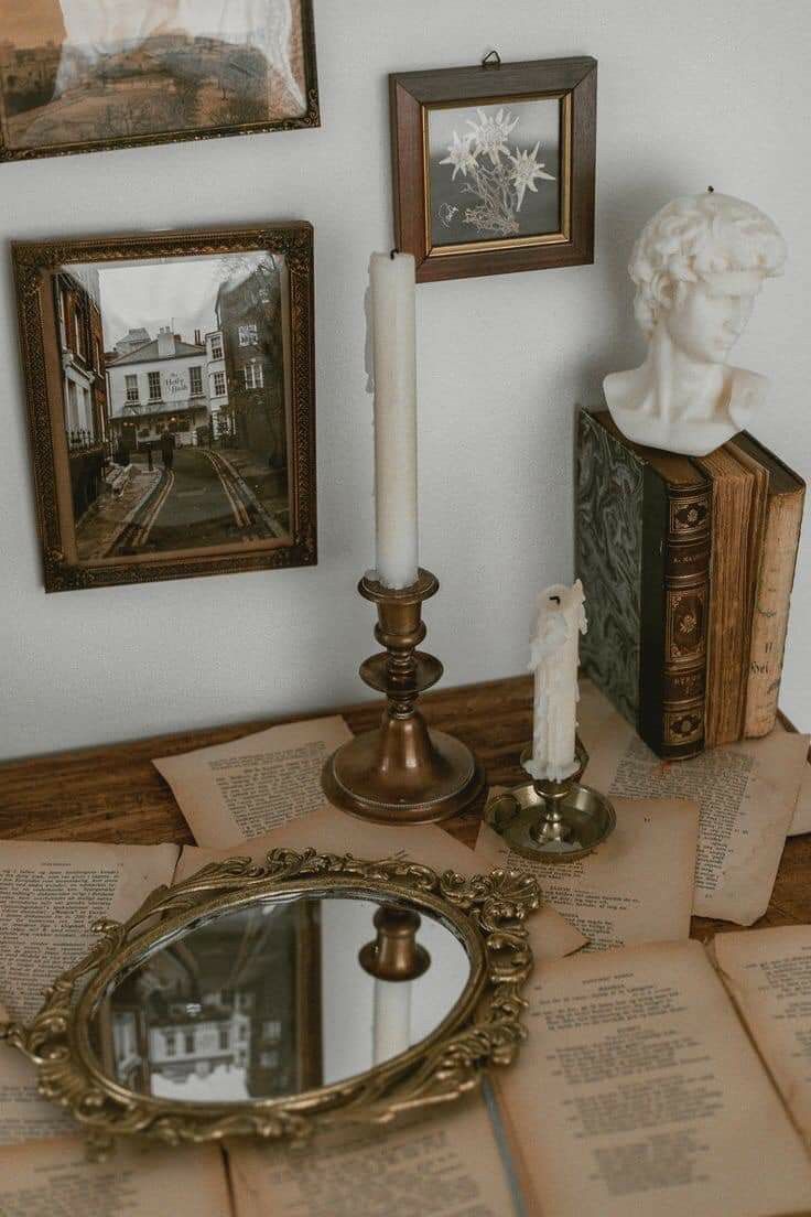 a table topped with books and a mirror next to a candle on top of it