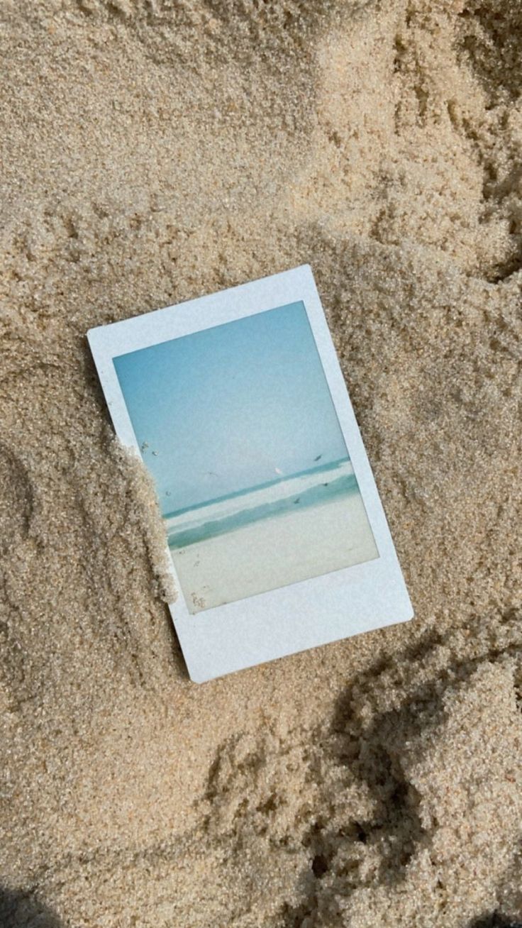 an old polaroid photo laying in the sand