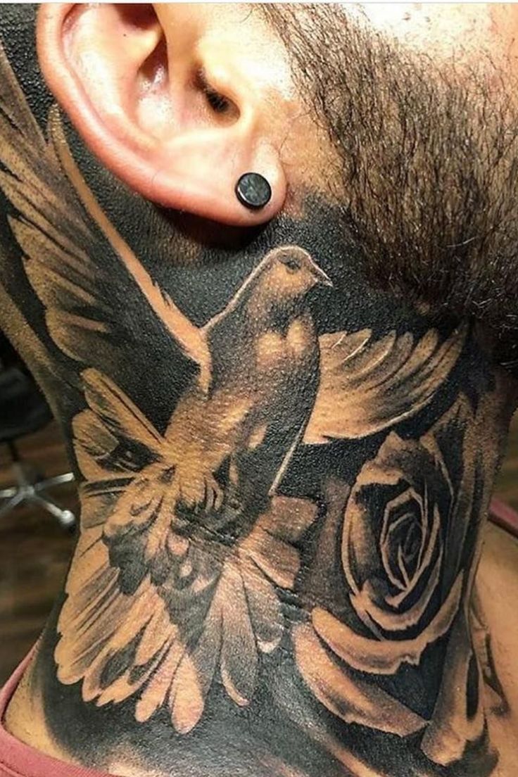 a man's neck with a bird and flower tattoo on it