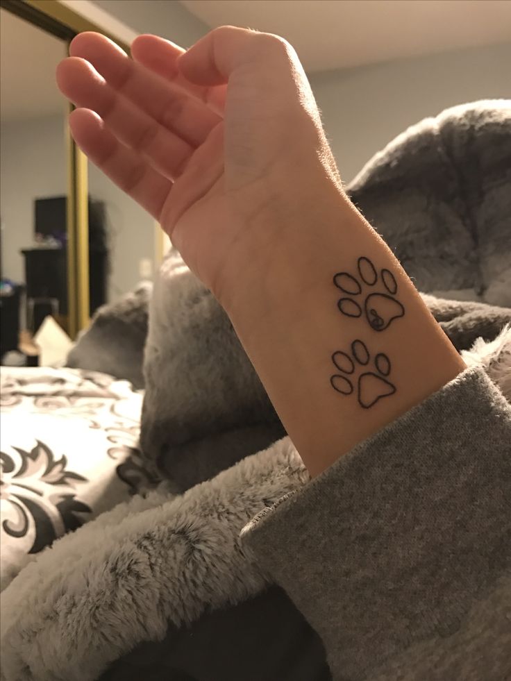 a person's arm with a tattoo on it that has two dogs paw prints