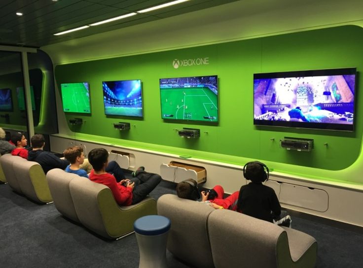 people sitting on couches watching televisions in a room with green walls and blue carpet