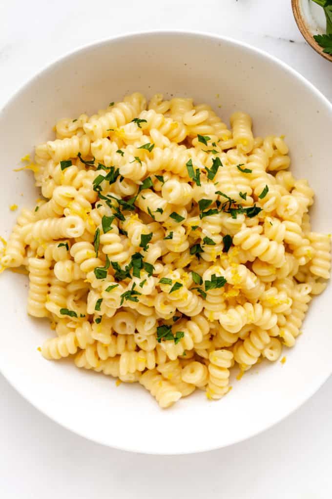 a white bowl filled with macaroni and cheese on top of a marble counter