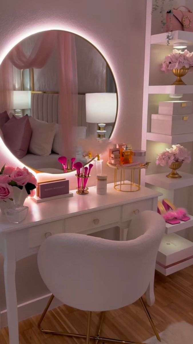 a white desk topped with a mirror next to a chair and pink flowers on top of it