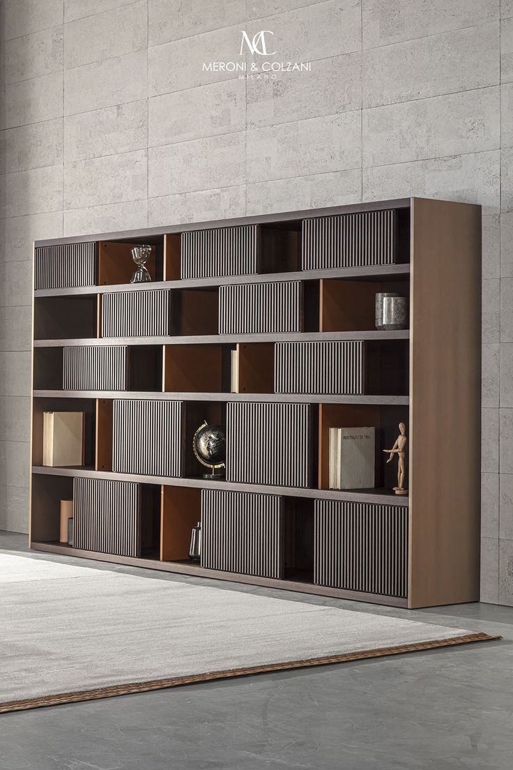 a book shelf with many books on it in front of a concrete wall and floor