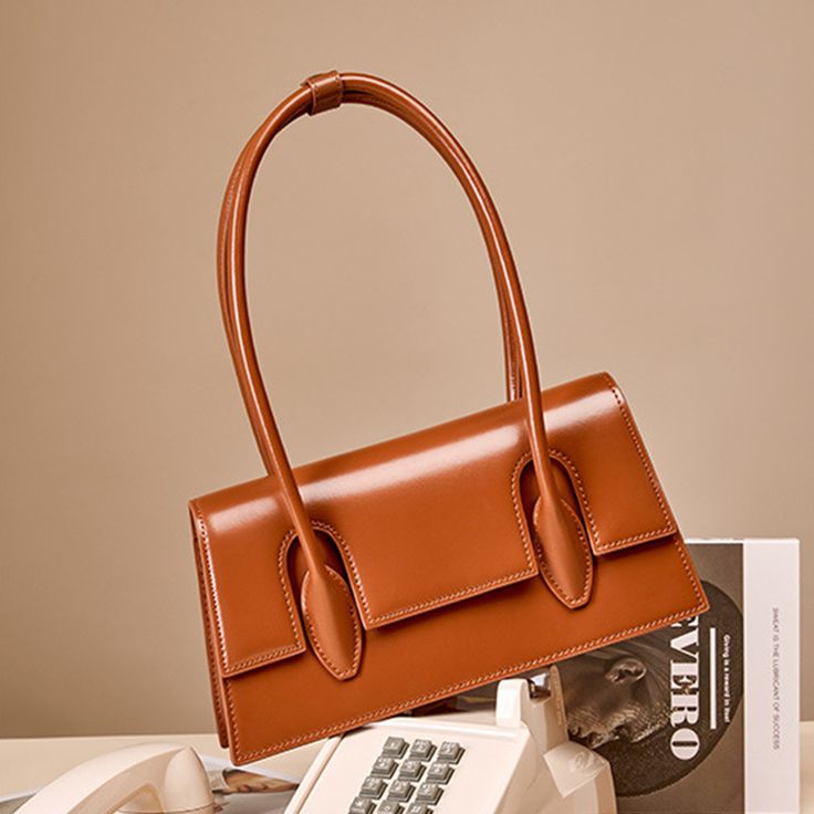 Featuring an of-the-moment trapeze silhouette and a minimalist aesthetic, this shoulder bag is a surefire way to flex your sartorial prowess. Between the clean lines and geometric silhouette, there is no shortage of design elements that make this style an ideal choice for minimalists. Let this statement piece put the finishing touch on an effortless ready-for-business outfit.Weight: 530 gWidth (cm): 7 cmHeight (cm): 14 Color: BrownInterior Material: PolyesterMaterial_bag: Two-Layer CowhideBagTyp Classic Large Capacity Baguette Satchel Bag, Chic Baguette Satchel For Daily Use, Classic Large Capacity Satchel Baguette Bag, Classic Baguette Shoulder Bag For Everyday Use, Classic Baguette Office Bag, Classic Baguette Bag For Office, Office Baguette Bag With Detachable Strap, Classic Office Baguette Bag With Detachable Strap, Modern Top Handle Shoulder Bag In Solid Color