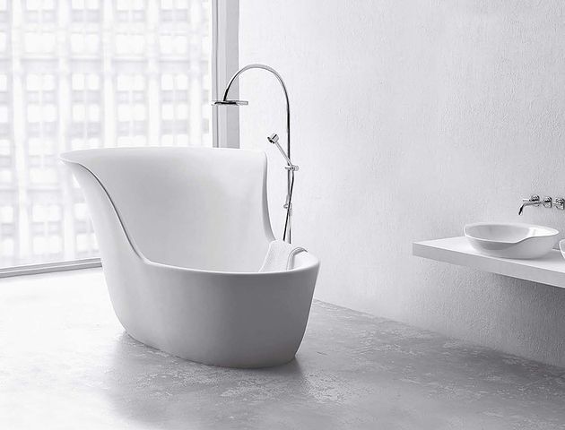 a white bathtub sitting next to a sink in a bathroom under a large window