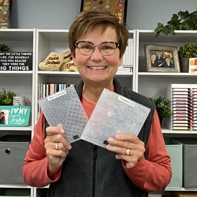 a woman holding two pieces of clear plastic in front of a book shelf filled with books