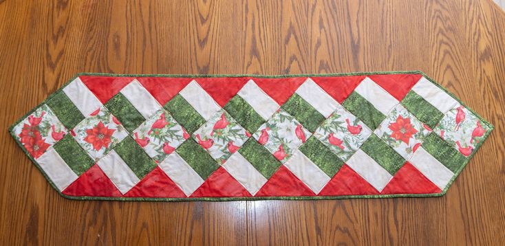 a red and green table runner sitting on top of a wooden floor