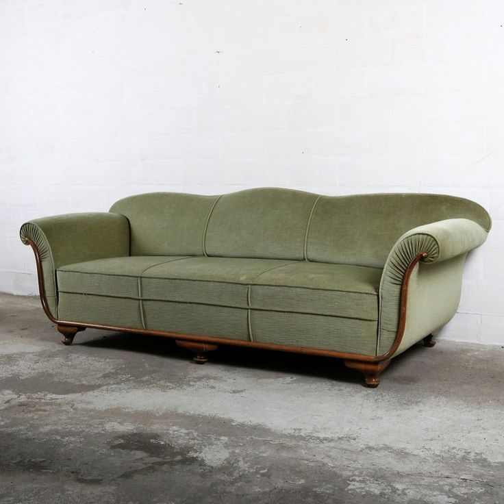 a green couch sitting on top of a cement floor next to a white wall in an empty room