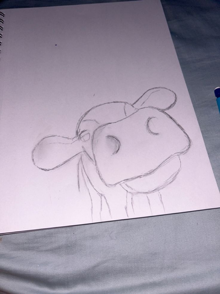 a drawing of a cow is shown on a sheet of paper next to a blue marker