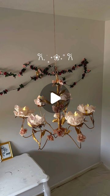 a chandelier hanging from the ceiling in a room with white furniture and flowers