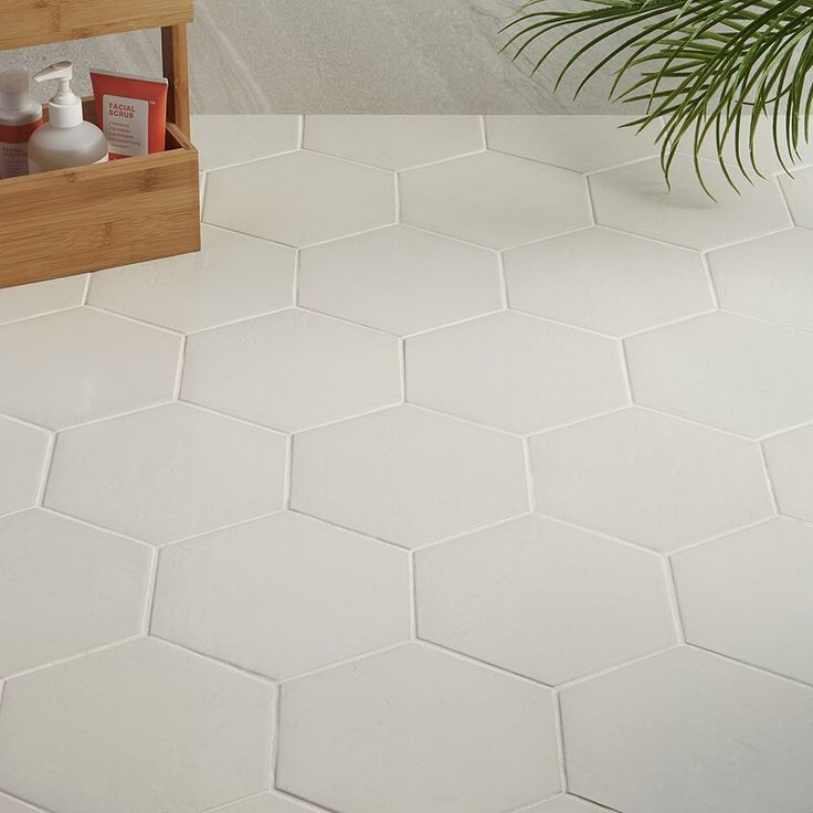 a bathroom with white hexagonal tiles on the floor and a potted plant