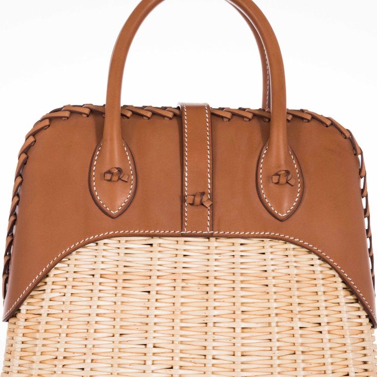 This Hermes Picnic Bolide, crafted in 2017, is an exquisite blend of rustic charm and refined elegance. This unique bag marries the natural beauty of Osier Wicker with the luxurious touch of Fauve Barenia leather, creating an accessory that is both visually stunning and tactilely inviting. The body of the bag is made from finely woven Osier Wicker, evoking the essence of serene summer days and elegant countryside escapades. This natural material adds an element of artisanal craftsmanship and giv Designer Natural Straw Bag With Bamboo Handle, Luxury Brown Straw Bag With Handles, Luxury Top Handle Straw Bag With Woven Leather, Luxury Brown Straw Bag With Leather Handles, Luxury Straw Bag With Braided Handles, Luxury Natural Straw Bag With Braided Handles, Luxury Straw Bag With Woven Leather Basket, Luxury Beige Leather Straw Bag, Luxury Woven Leather Basket Bag